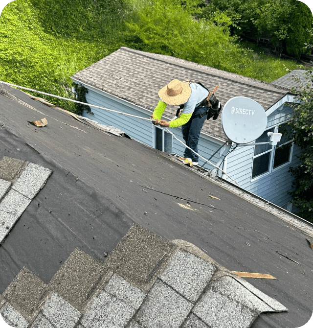 A man on the roof of a house with a yellow hat.