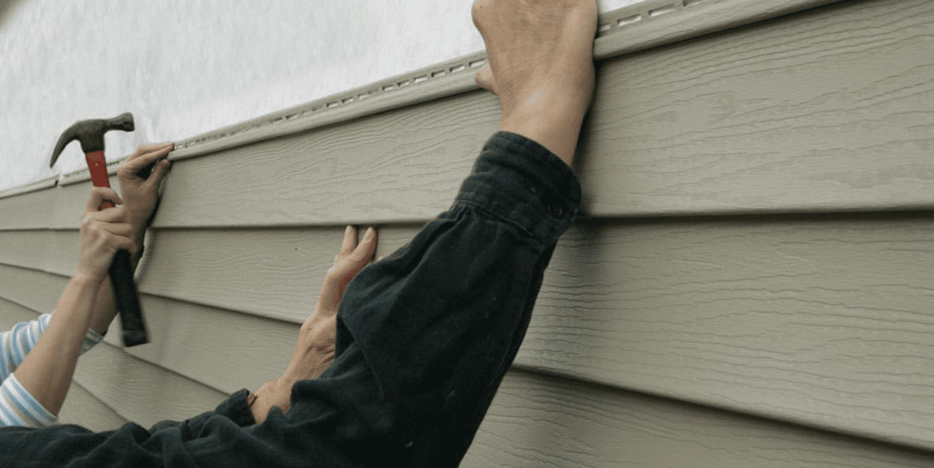 A person holding onto the side of a house