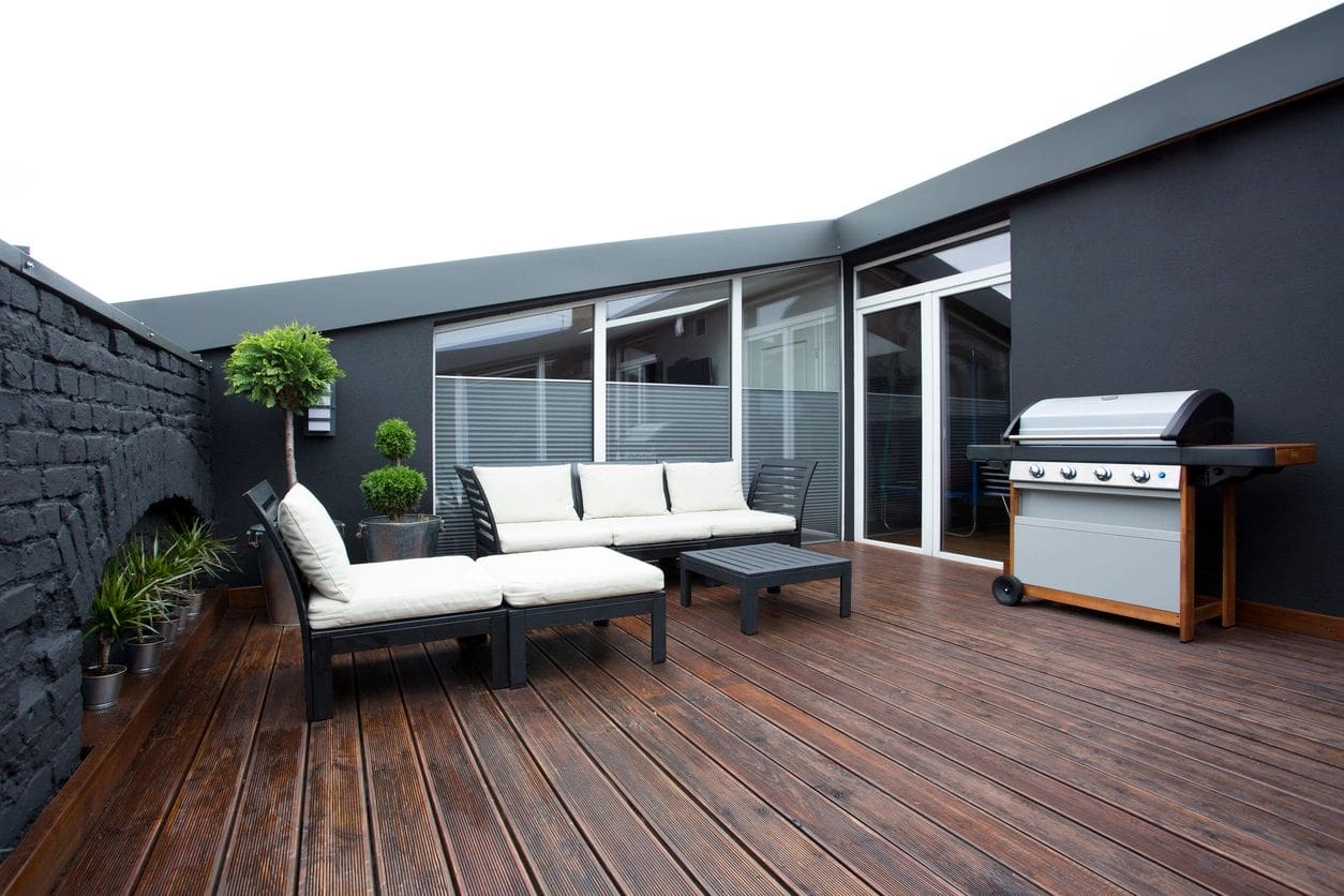 A patio with furniture and a grill on the back deck.